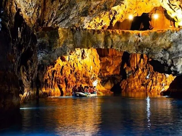 Group in a raft exploring an illuminated cave with dramatic rock formations
