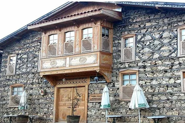 Nahaufnahme eines traditionellen Steingebäudes mit kunstvoll geschnitzten Holzfenstern und Holztür