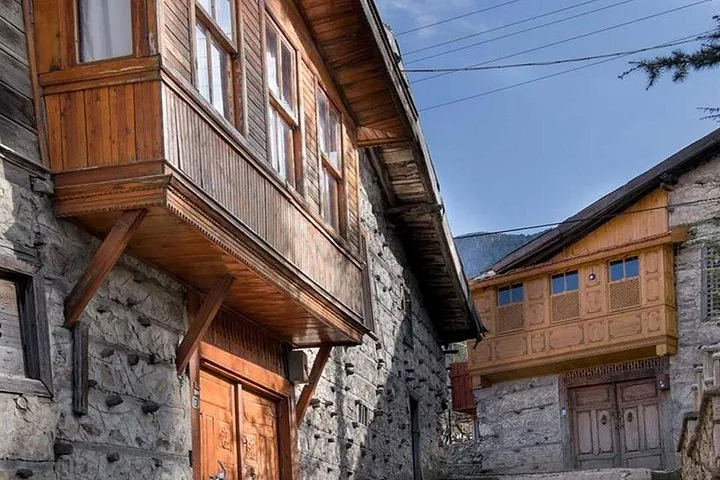 Blick in eine enge Gasse zwischen zwei traditionellen Stein- und Holzhäusern mit Balkonen