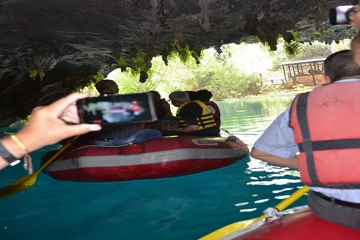 Person, die mit einem Smartphone ein Foto von einer Gruppe in einem roten Schlauchboot in einer Höhle macht