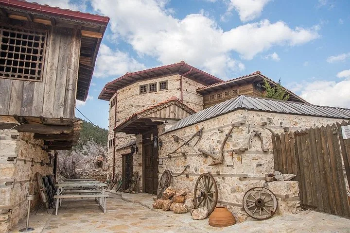 Patio de un edificio tradicional de piedra con elementos de madera y antiguas herramientas agrícolas expuestas